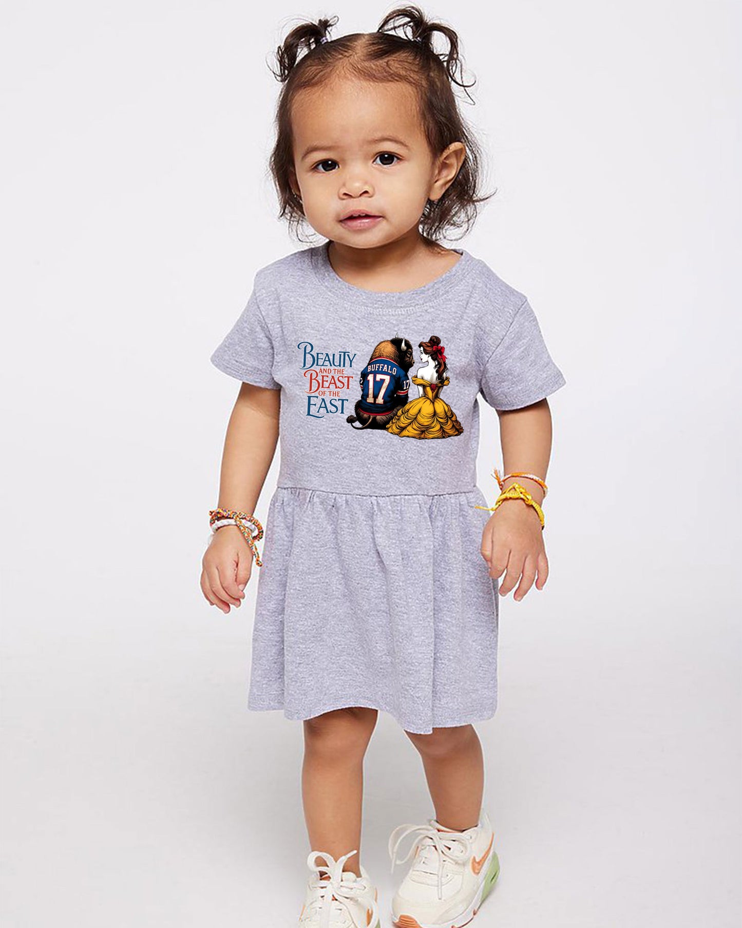 Child wearing a gray dress with 'Beauty and the Beast' print on a white background